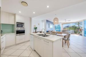 a kitchen with white cabinets and a table and a dining room at C Bargara Unit 101 in Bargara