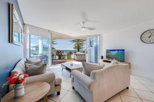 a living room with two couches and a clock at C Bargara Unit 101 in Bargara
