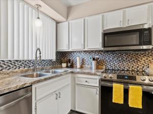 a kitchen with white cabinets and a sink and a microwave at All About Alaska in Anchorage