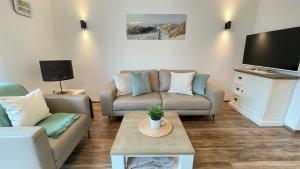 a living room with a couch and a tv at Strandbox & Strandresidenz in Norderney