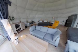 a living room with a couch and a bed in a tent at GRAMPING STAY TOMAMU in Tomamu