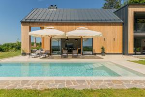 a house with a pool and two umbrellas at Blacksmith house - SPA, Heated outdoor pool, Kids zone in Varaždinske Toplice