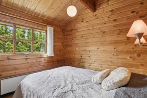 a bedroom with wooden walls and a bed with a window at Peaceful Holiday Home Close To Nature in Glesborg
