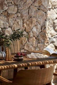 a wooden table with a stone wall and a book at Memorias Villas and Suites in Vasilikos
