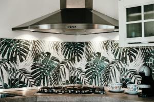 a kitchen with a stove top with a tropical wallpaper at VILLA INDIPENDENTE AL MARE BUDONI in Tanaunella