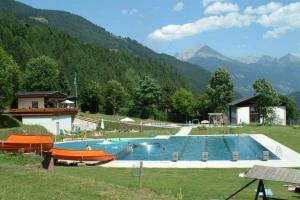 uma grande piscina num campo com montanhas ao fundo em Hotel Gletschermühle em Flattach