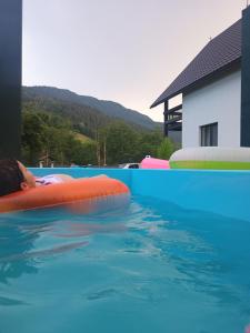 a little girl laying on an inner tube in a swimming pool at Casa Noastră in Vidra