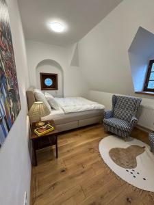 a bedroom with a bed and a chair and a table at Apartmán - Ostrůvek 203 in Lesná