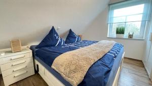 a bedroom with a bed with blue pillows and a window at Strandbox & Strandresidenz in Norderney