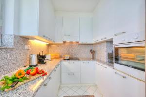 a kitchen with white cabinets and vegetables on a counter at Residenza Parco Carona with Lake-View - Happy Rentals in Lugano