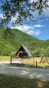 a barn in a field with a hill in the background at Vila Jezero-Jajce in Jezero