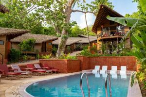 a resort pool with lounge chairs and a house at SAMA The Silver Creek in Bogmalo