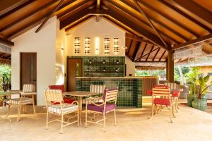 a patio with tables and chairs and a bar at SAMA The Silver Creek in Bogmalo