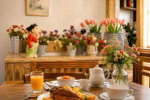 a table with a breakfast of orange juice and flowers at Villa Lunka in Nuwara Eliya