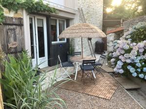 a patio with a table and umbrella and flowers at Au duplex in Chantonnay +6 photos