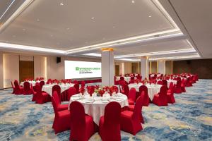 a conference room with tables and red chairs and a screen at Wyndham Garden Haikou Meilan in Haikou +106 photos
