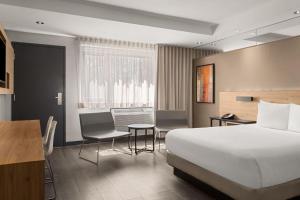 a hotel room with a bed and a table and chairs at Ramada by Wyndham Laval in Laval