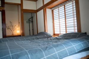 a bedroom with a blue bed and a window at The Alpen House Omachi in Omachi