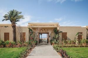 a building with a palm tree and a walkway at Sakhra Hotel & Spa, Almaza Bay in Marsa Matruh