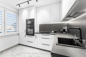 a kitchen with white cabinets and a sink at Korsako apartamentai in Šiauliai
