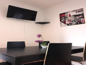 mesa de comedor negra con sillas y TV de pantalla plana en Apartment Am Ring, en Bochum