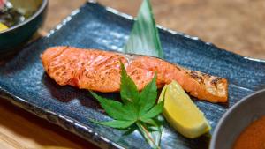 a blue plate with a piece of fish and a lemon at YOU STYLE HOTEL HAKATA in Fukuoka