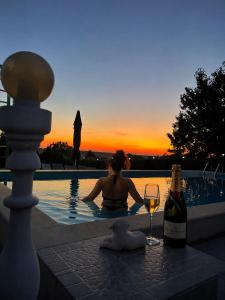a woman sitting in a swimming pool with a glass of wine at Erida Guest House - къща за гости до Русе in Trastenik