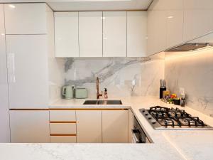 a white kitchen with white cabinets and a sink at Skyline Views Premium 2B2B Free Parking Box Hill in Box Hill