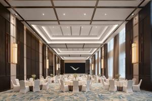 a banquet hall with white tables and white chairs at Mövenpick Kaifeng West Lake in Kaifeng