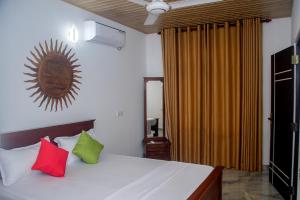 a bedroom with a bed with red and green pillows at Breeze 12 Villa in Negombo