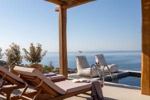 a patio with chairs and a view of the ocean at Villa Lefko in Ano Syros