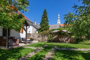 a yard with a building and a church with a tower at Köveskál Vendégház in Köveskál