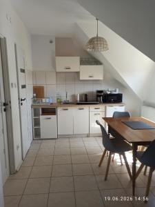 a kitchen with white cabinets and a wooden table at pokoje do wynajecia in Giżycko