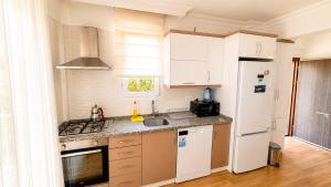 a kitchen with white cabinets and a white refrigerator at Fethiye Merkezde Lüx Daire in Fethiye +20 photos