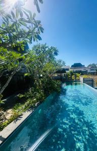 a swimming pool with blue water and trees at The balangan studio room 7 in Bingin Beach