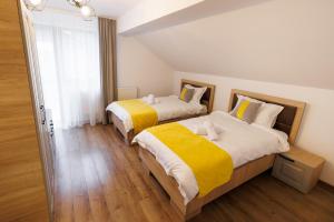 a bedroom with two beds with yellow and white sheets at Vila MIHAI in Văliug