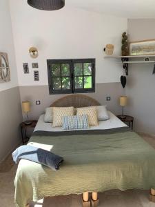 a bedroom with a large bed with two windows at Les Vergers des Maures in La Garde-Freinet