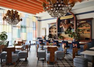 a restaurant with tables and chairs and a chandelier at Graduate by Hilton Auburn, AL in Auburn