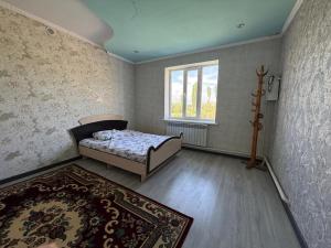 a bedroom with a bed and a window and a rug at Tunduk House 14 in Bash-Kayyngdy