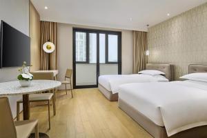 a hotel room with two beds and a table at Hyatt Place Shanghai Lingang in Zhenghai +35 photos