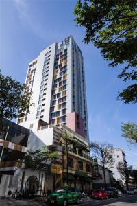 a tall building with a green car in front of it at Wink Danang Centre, Unscripted by Hyatt - 24 Hours stay in Danang