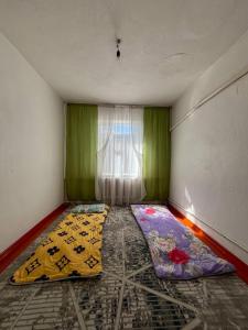 a room with two beds in front of a window at Begimay Inn in Toguz-Bulak
