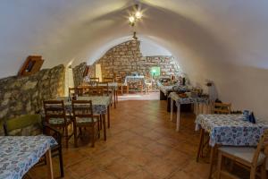 a restaurant with tables and chairs and a stone wall at Köveskál Vendégház in Köveskál