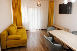 a living room with a yellow couch and a table at Vila MIHAI in Văliug