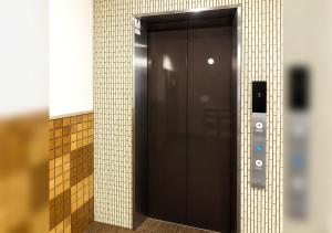 a elevator door in a bathroom with a tile wall at Floral Hotel Mari-Kyoto in Kyoto
