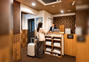 two women standing at a cash register in a store at Floral Hotel Mari-Kyoto in Kyoto