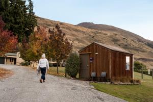 a woman walking down a gravel road next to a smallshed at Tasman Holiday Parks - Wanaka in Wanaka