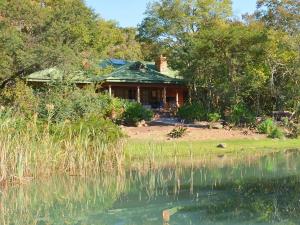 a house sitting next to a body of water at Ntsinini Trout & Leisure Farm in Waterval Boven