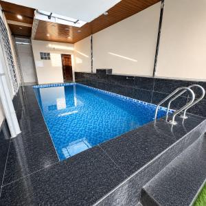 a large swimming pool with a black tile floor and black tiles at Sagar Villa Udaipur in Udaipur