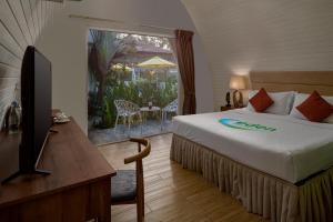a bedroom with a bed and a television and a patio at Eden Beach Resort by EHM in Koh Rong Sanloem
